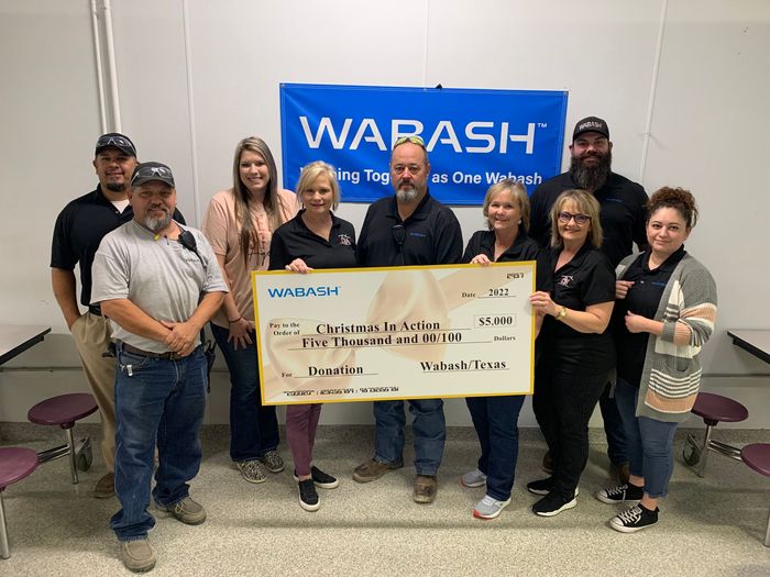 Group of people posing indoors with an oversized check in front of a WARASH banner.